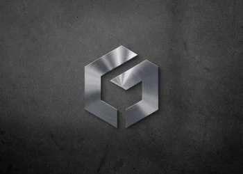 Realistic chrome embossed logo effect on grey interior office wall by LogoGrids, free PSD download.