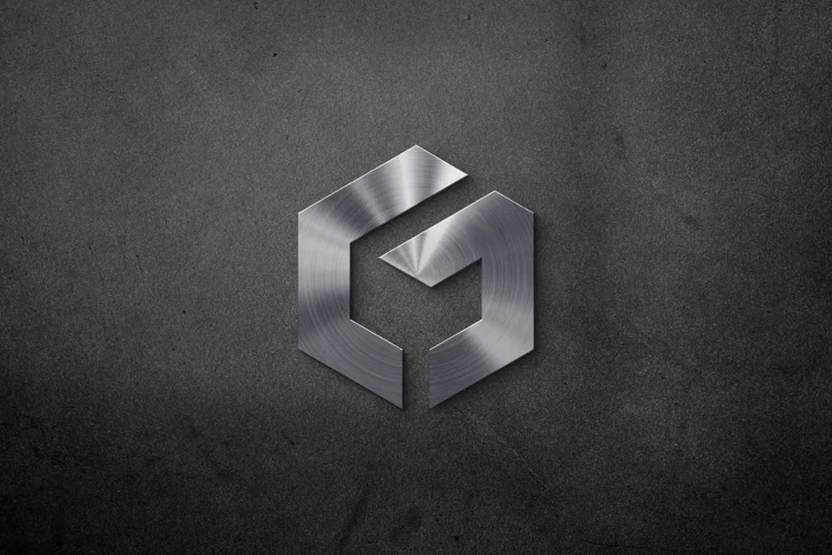 Realistic chrome embossed logo effect on grey interior office wall by LogoGrids, free PSD download.